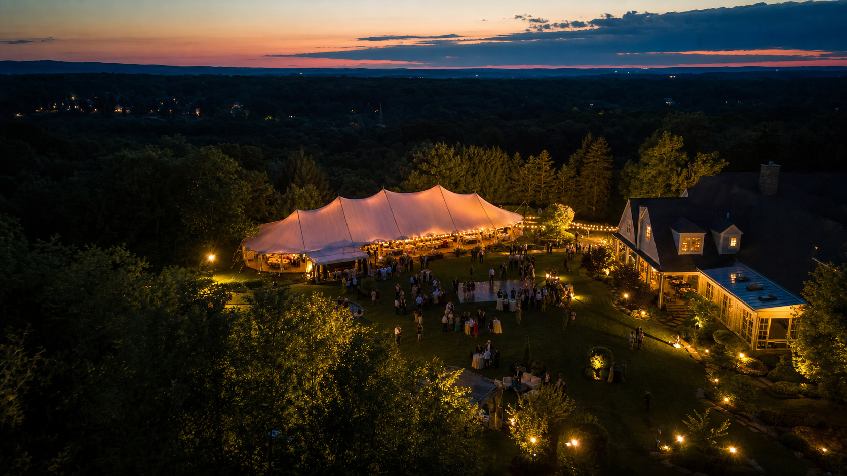Aerial night photograph of a private outdoor event with a lit tent