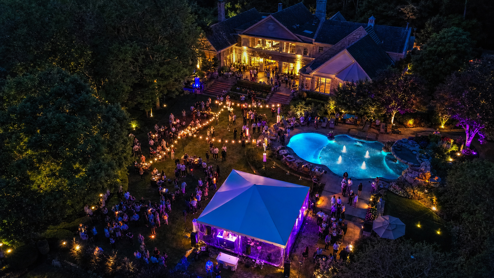 Aerial photograph of a backyard estate party with pool and string lights at twilight