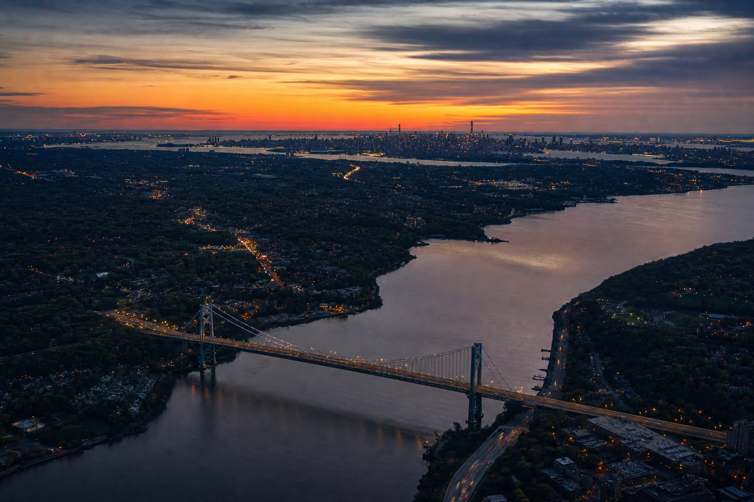 Aerial photograph of the tri-state region at dusk with a bridge and Manhattan skyline in the distance